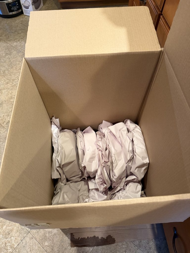 Wrapped glass bowls and plates packed on their side in a moving box — Aron Movers